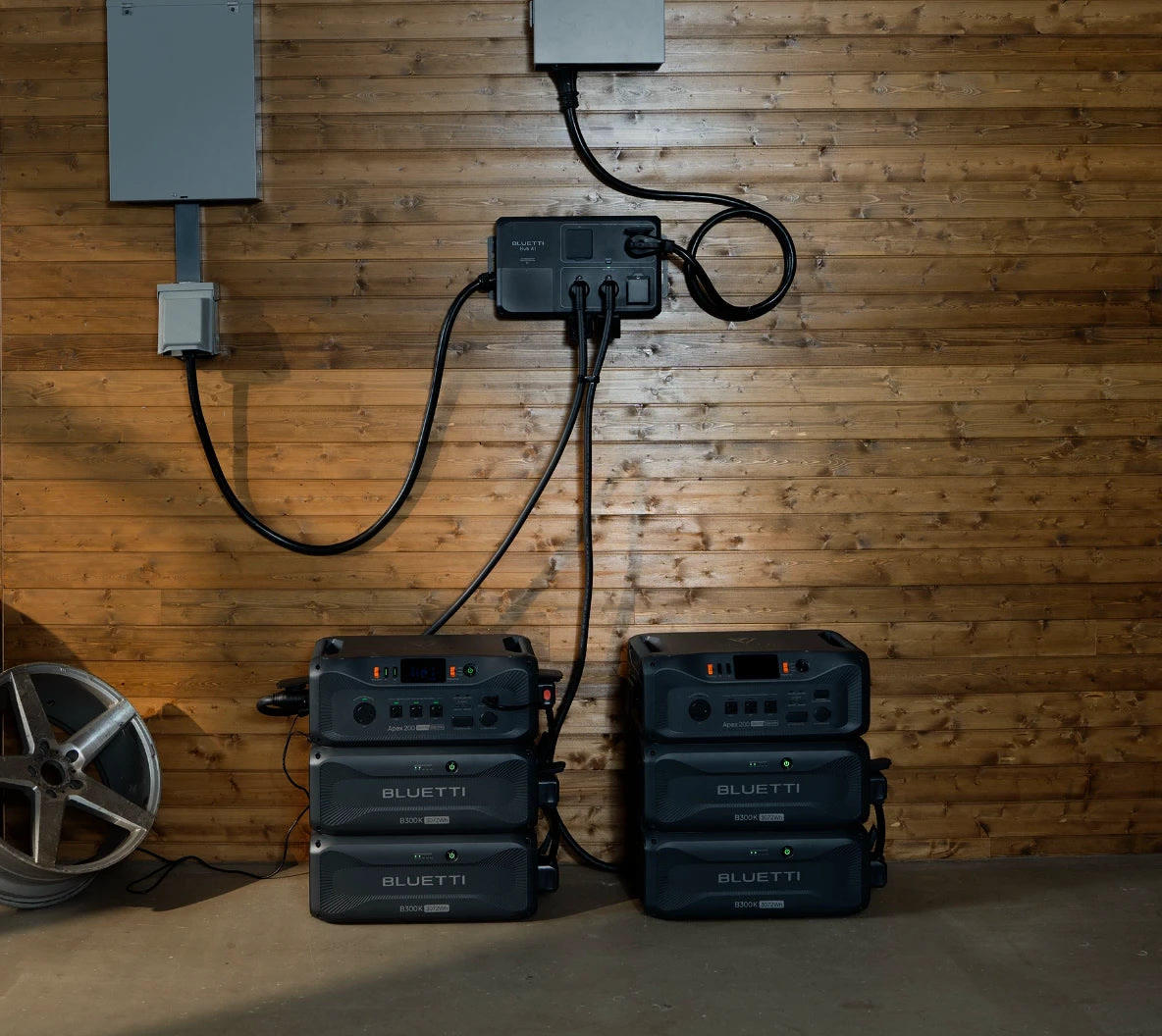 BLUETTI image of two Apex 200 units, each stacked on two B300K expansion batteries, cabled to a wall-mounted BLUETTI Hub A1 beside an electrical panel in a garage